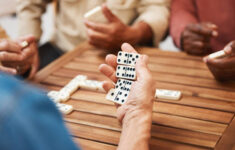 tangan domino dan teman teman dalam permainan papan di atas meja kayu untuk kegiatan yang